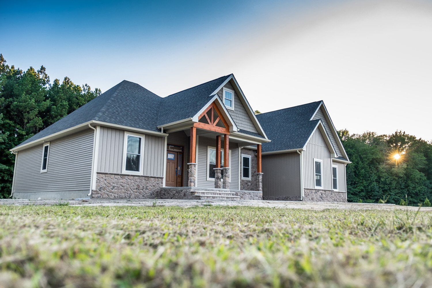 A cozy house with a spacious front porch and a neatly landscaped front yard.